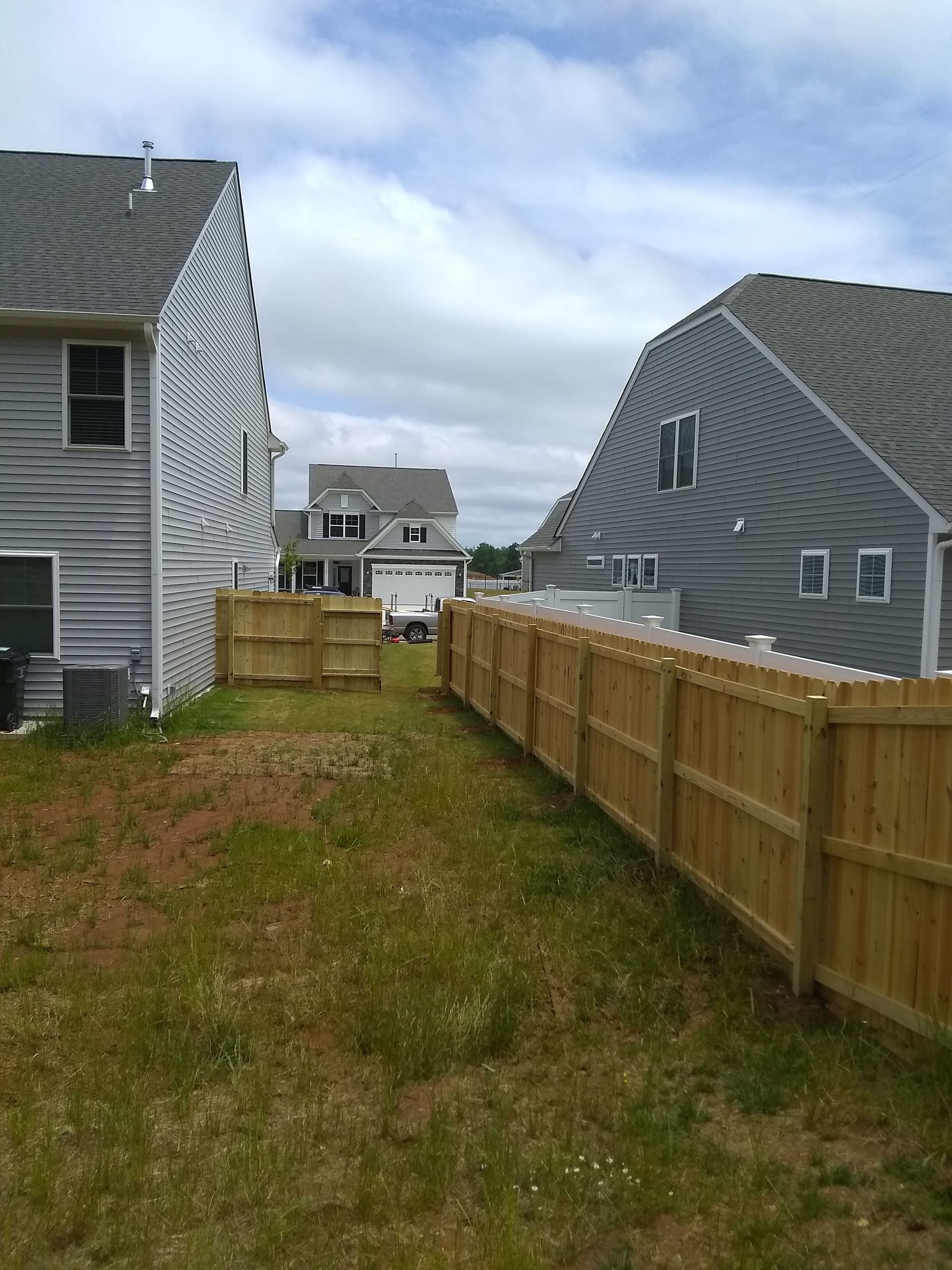 A wooden fence is sitting on top of a lush green lawn in front of a house.