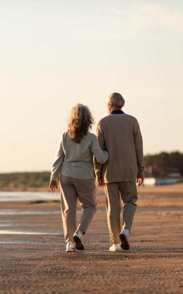 Two people walking hand in hand on a beach at sunset