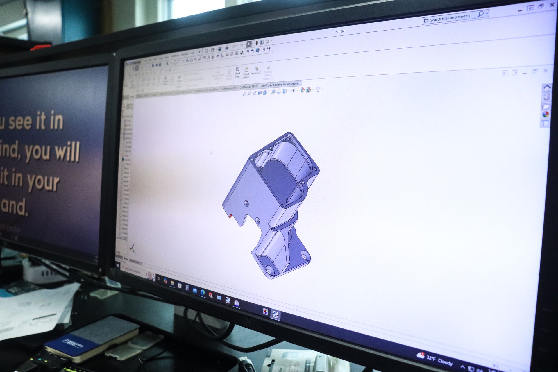 A computer monitor displays a 3d model of a piece of metal