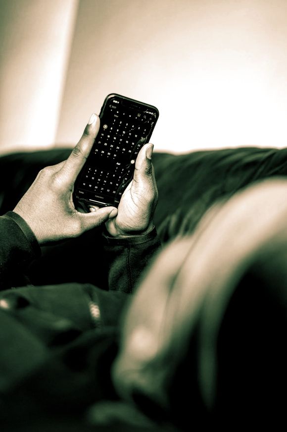 A person is laying on a couch using a cell phone