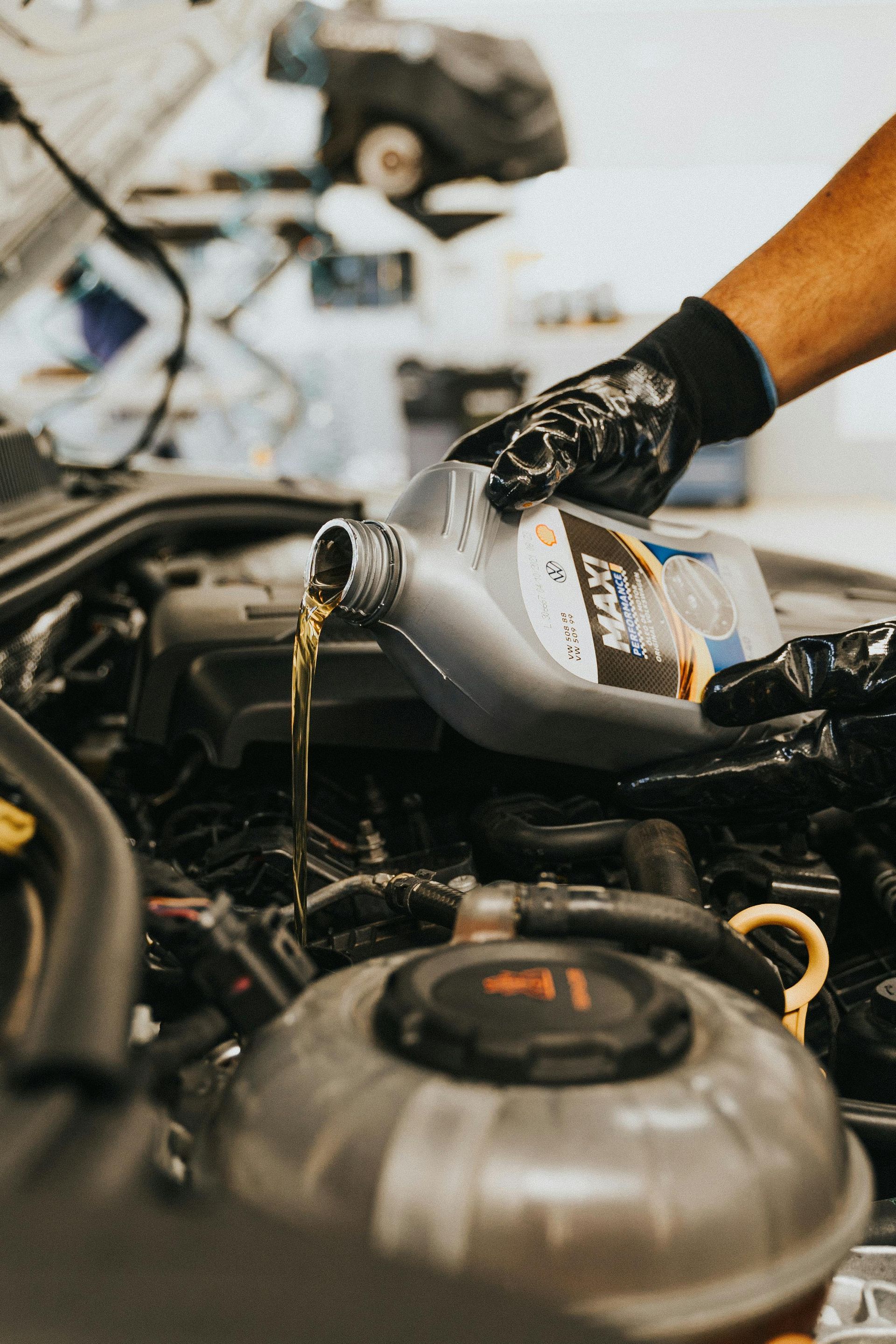 A person is pouring oil into a car engine. | 299 Automotive