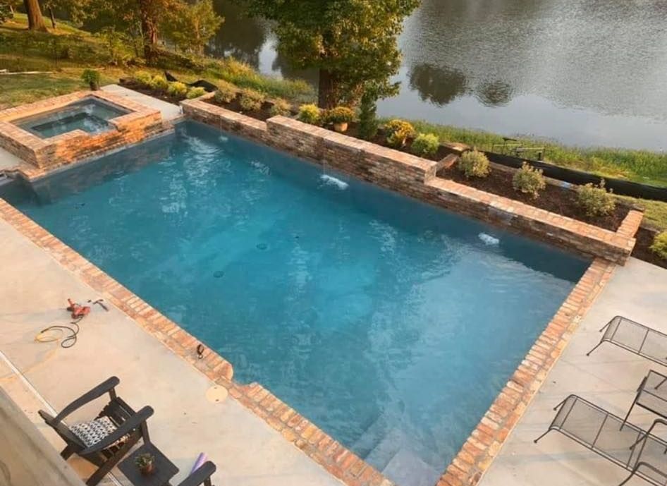 An aerial view of a large swimming pool with a hot tub in the backyard.