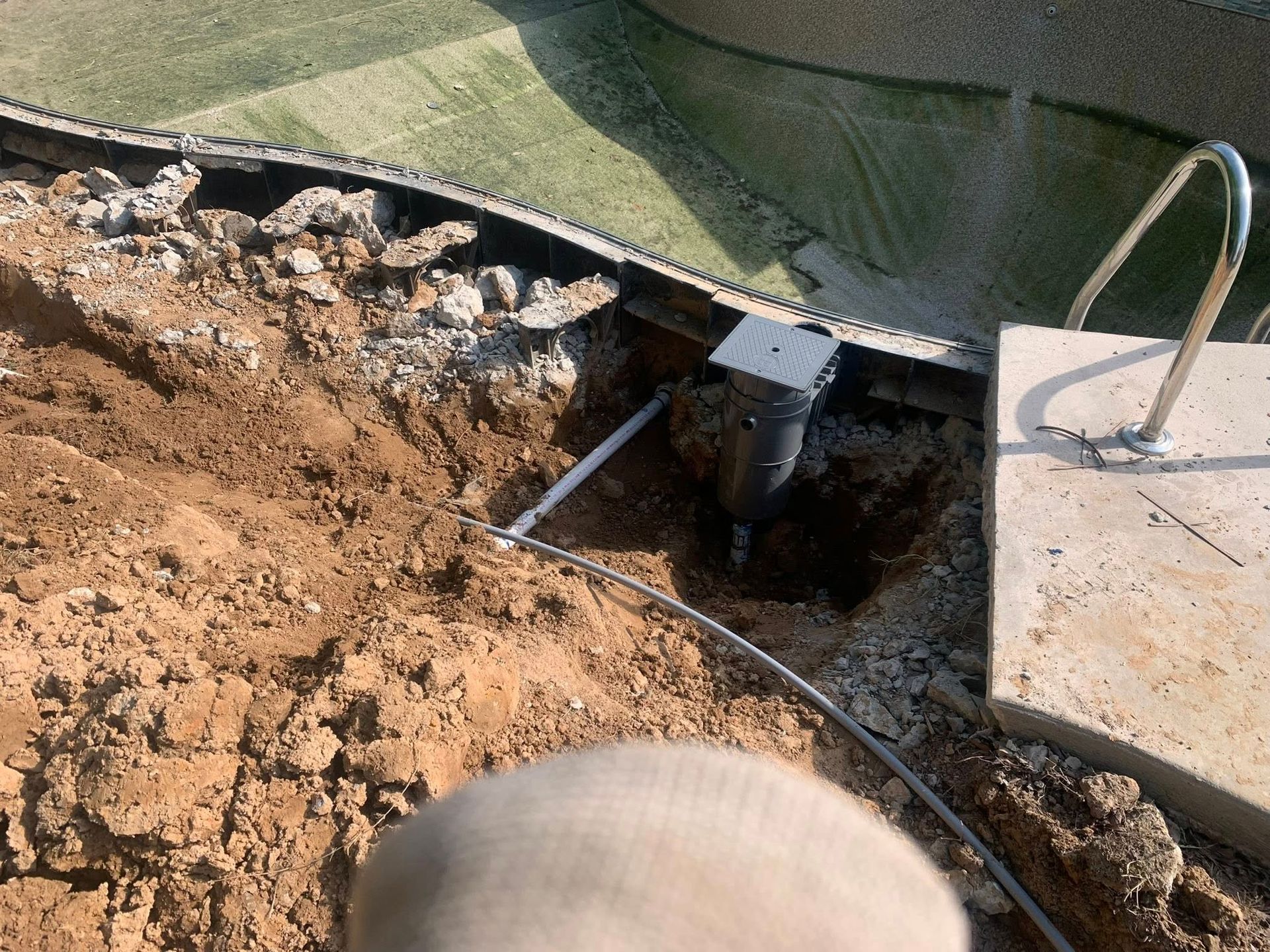 A person is digging a hole in the ground near a pool