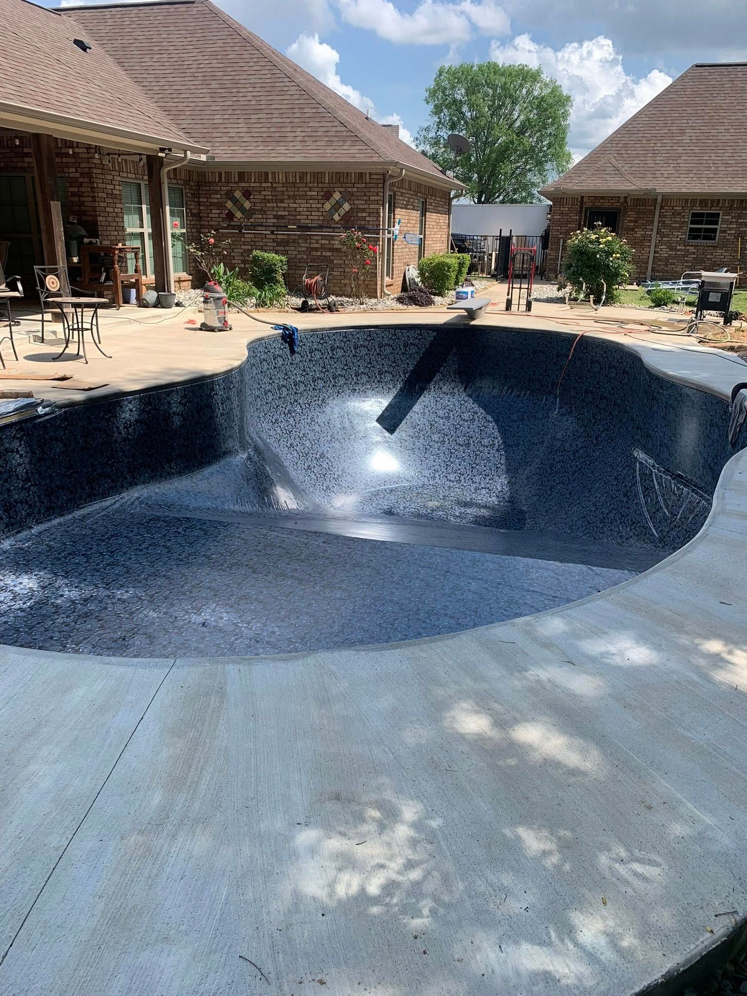 A large swimming pool is being built in the backyard of a house.