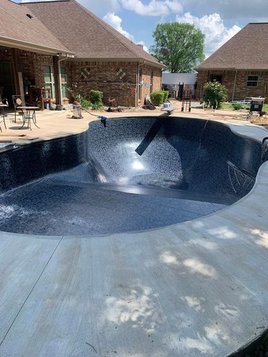 A large swimming pool is being built in the backyard of a house.