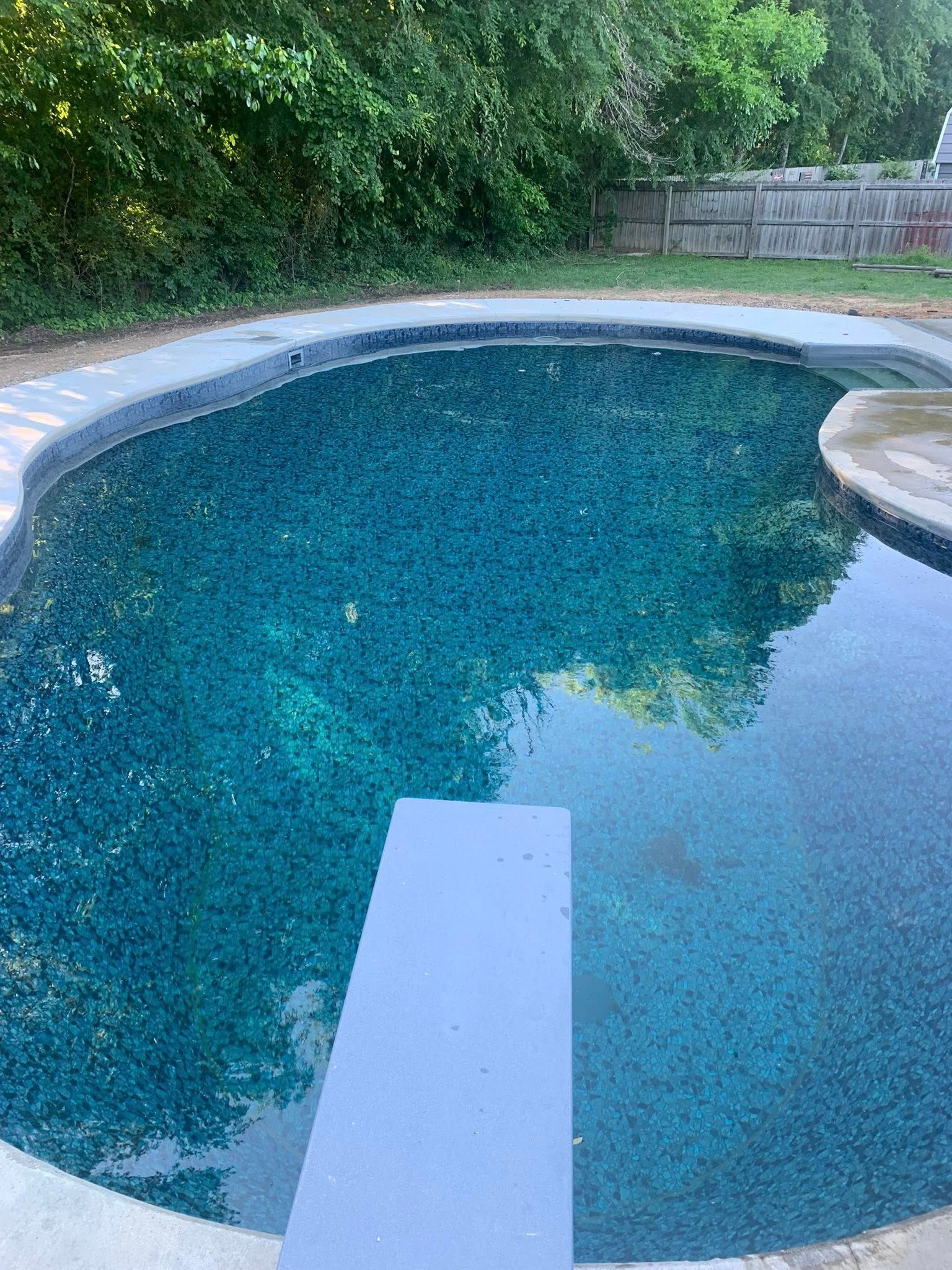 A large swimming pool with a diving board in the middle of it.