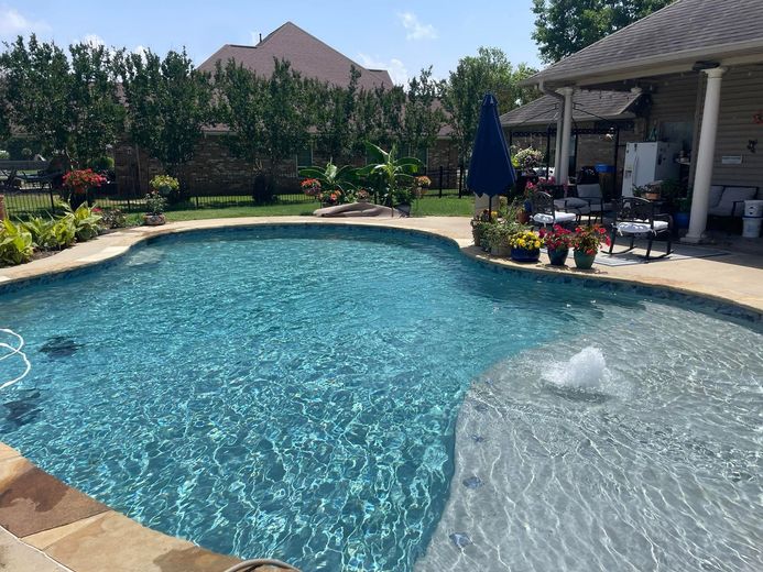 A large swimming pool with a fountain in the middle of it.