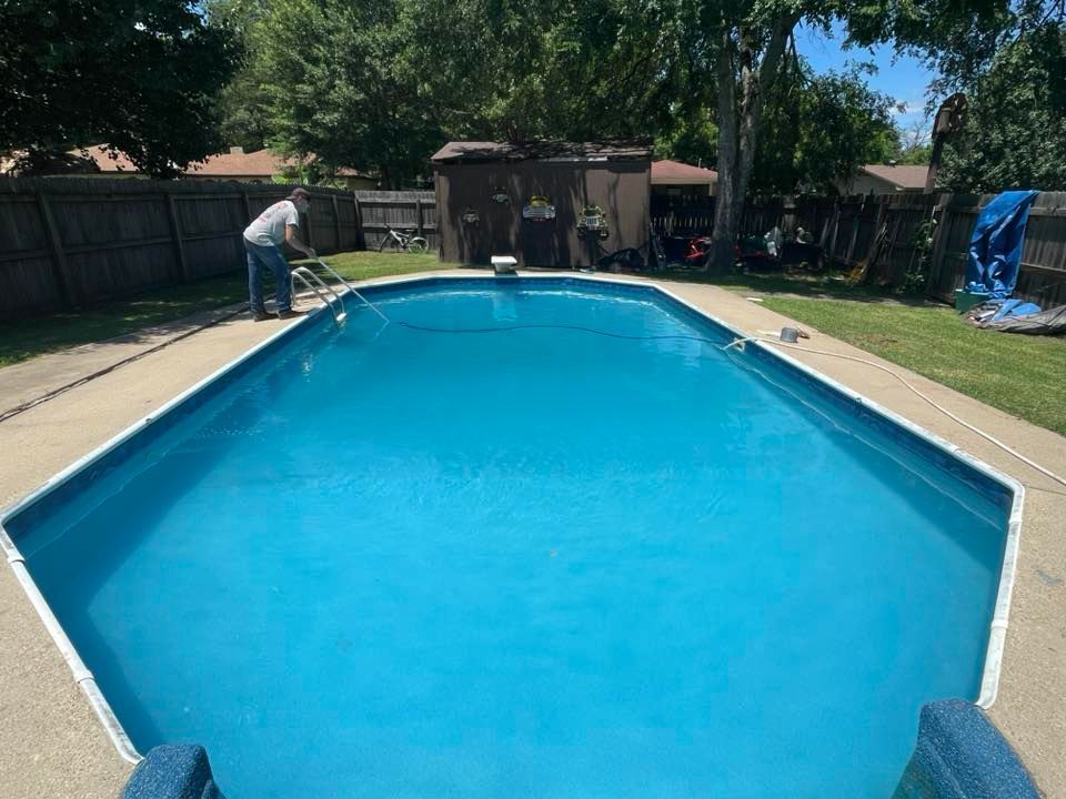 A man is standing next to a large swimming pool.