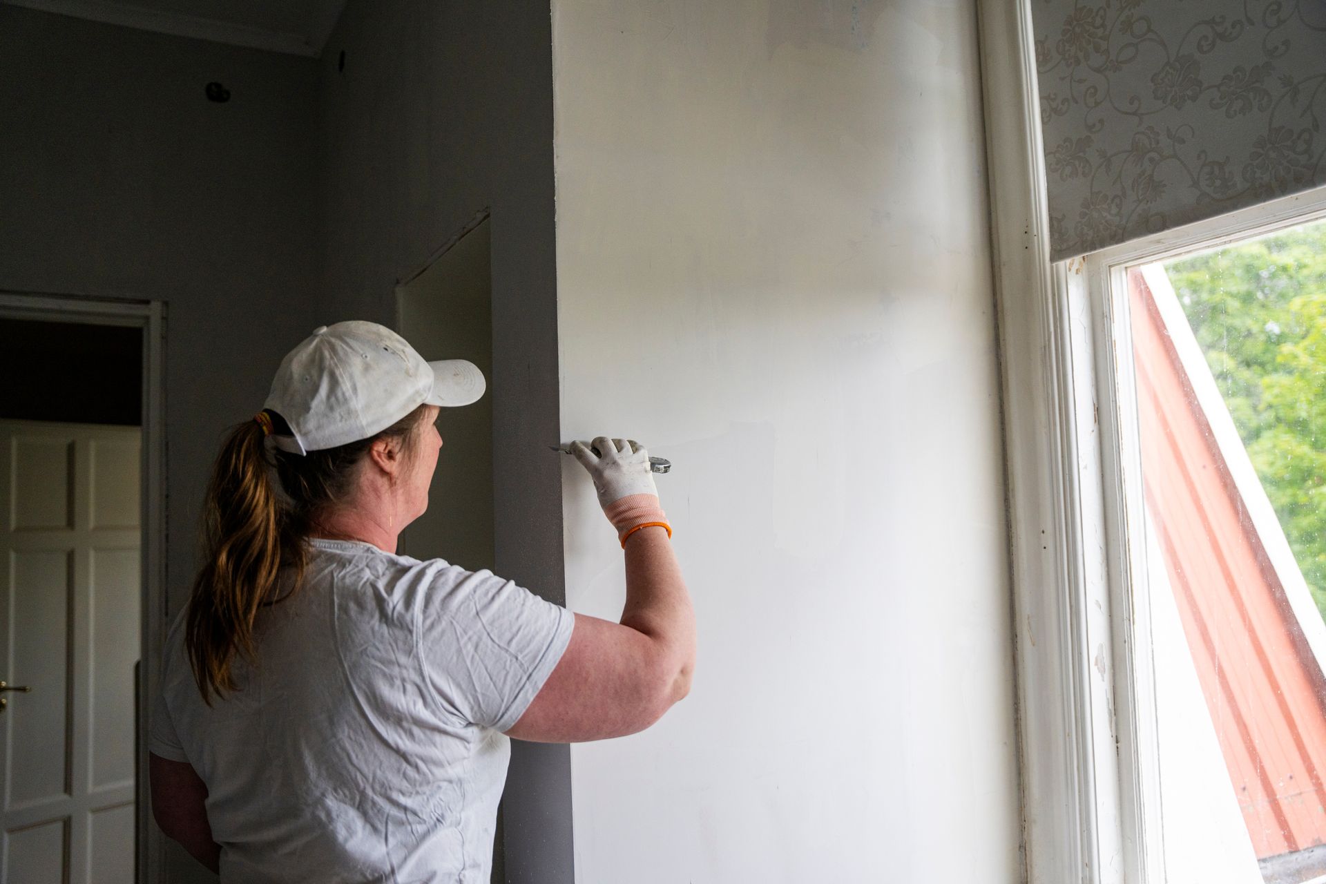 Rear view of female repairperson plastering wall at a site.
