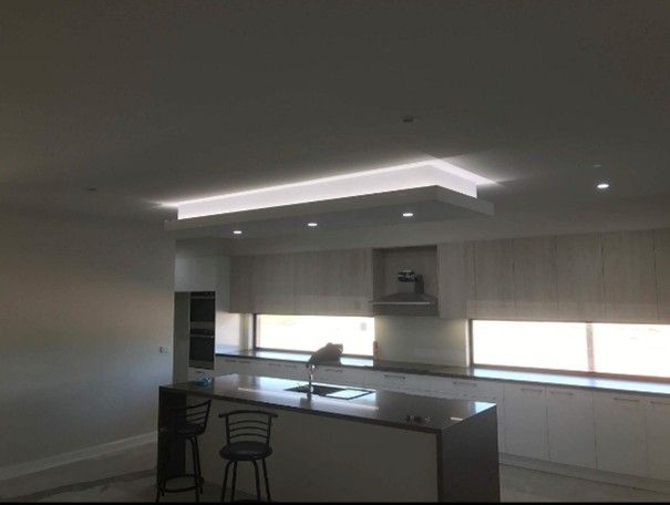 View of a modern kitchen with light cabinets and a dark counter, after residential plastering.