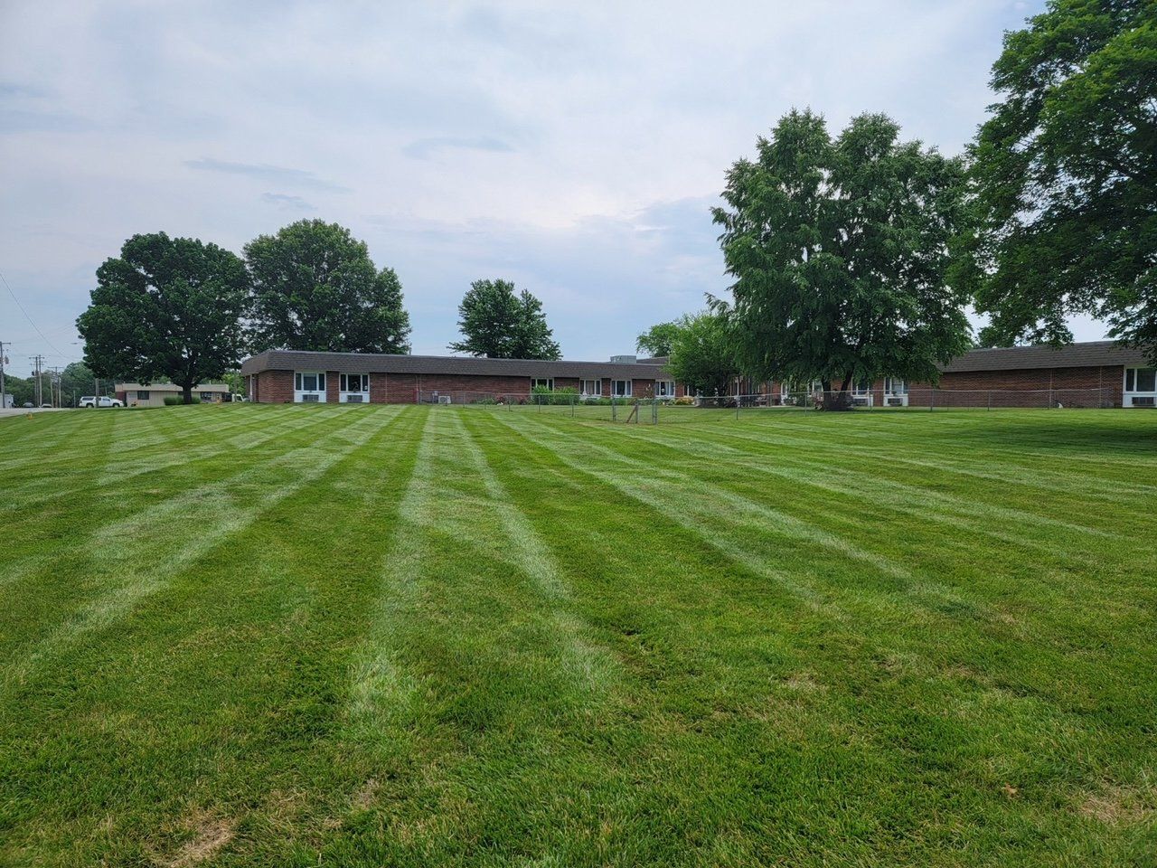 A large lush green field with a house in the background.