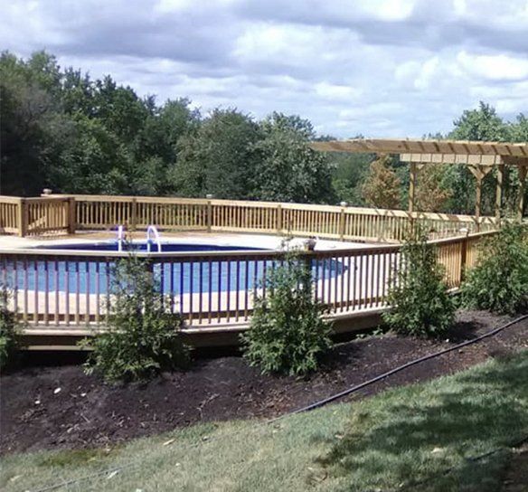 A large swimming pool with a wooden deck and pergola