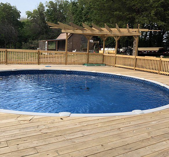 A large swimming pool surrounded by a wooden deck and fence