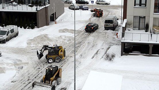 A snow plow is driving down a snowy street.