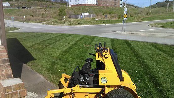 A yellow lawn mower is sitting on top of a lush green lawn.