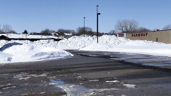 A snowy parking lot with a fire bay building in the background