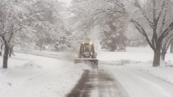 A snow plow is clearing a snow covered road.