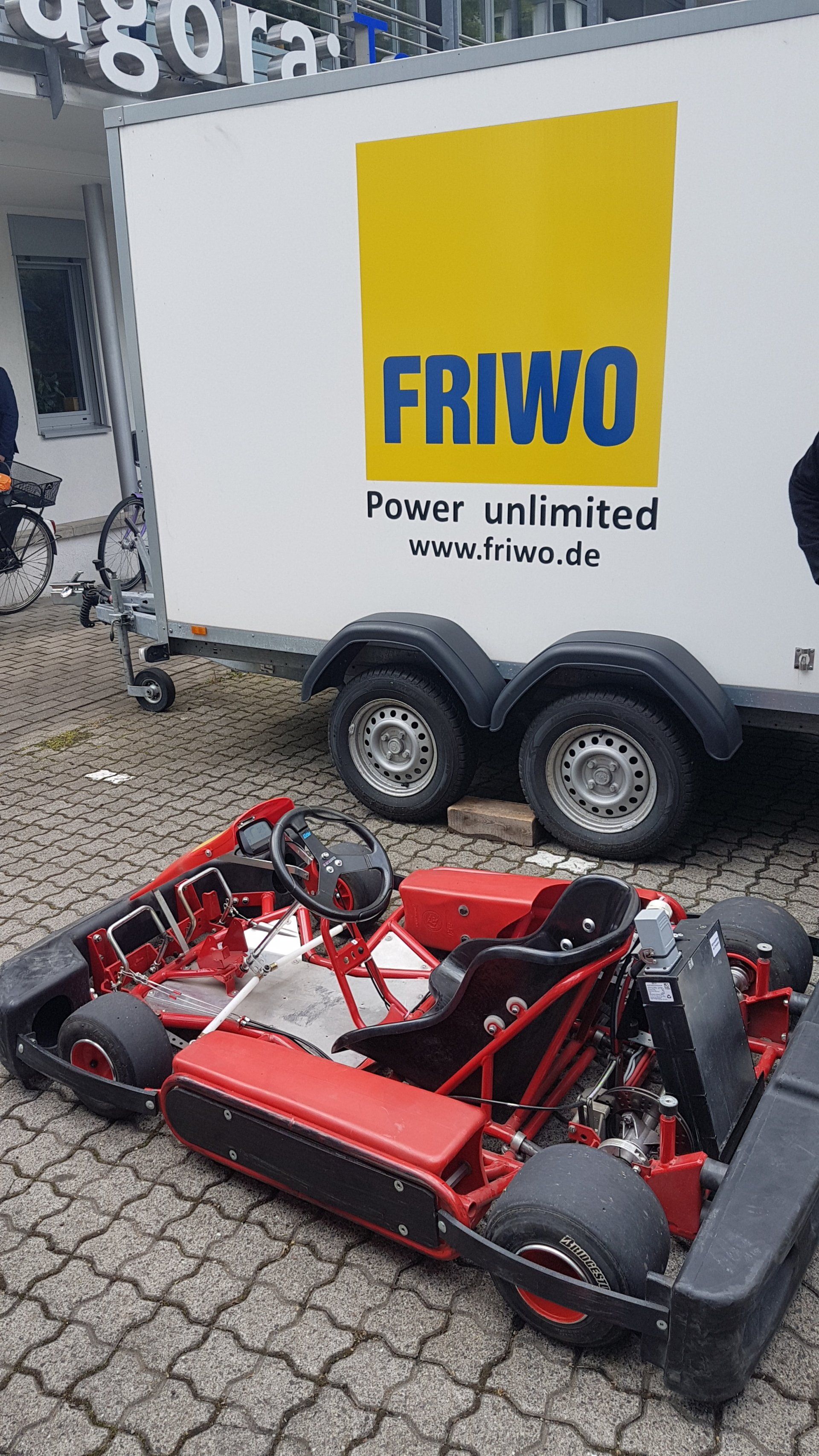 A go kart is parked in front of a friwo trailer.