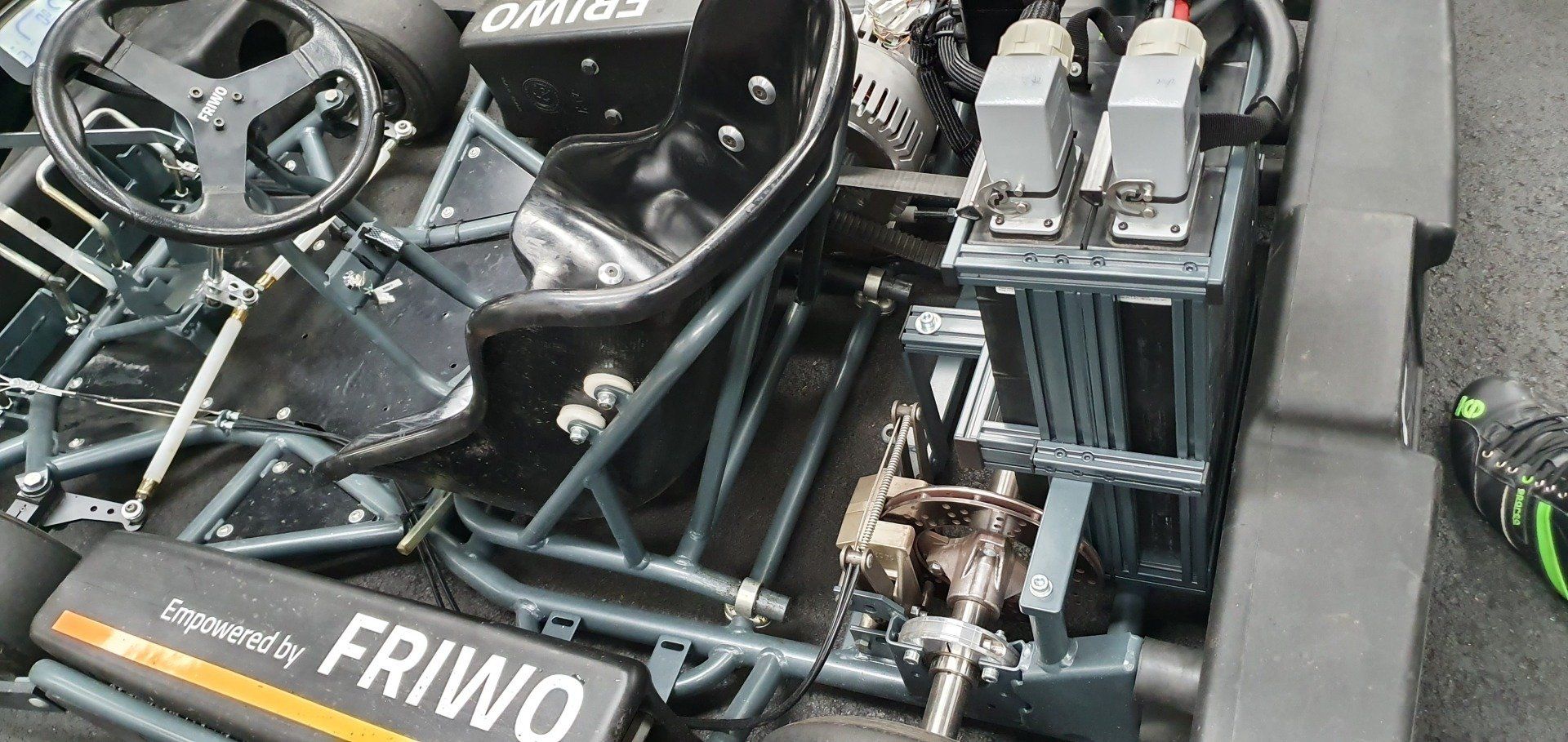 The inside of a race car with a steering wheel and a battery.