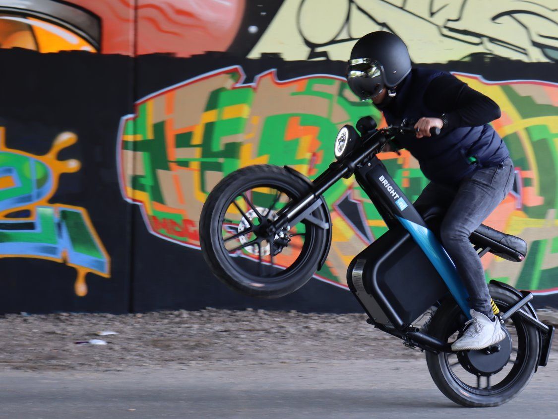A man wearing a helmet is doing a trick on a motorcycle