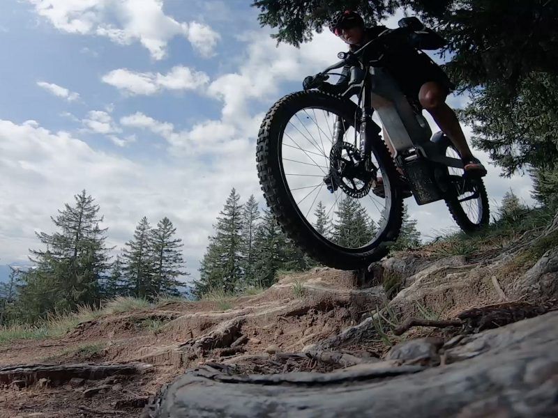 A person is riding a bike on a trail in the woods
