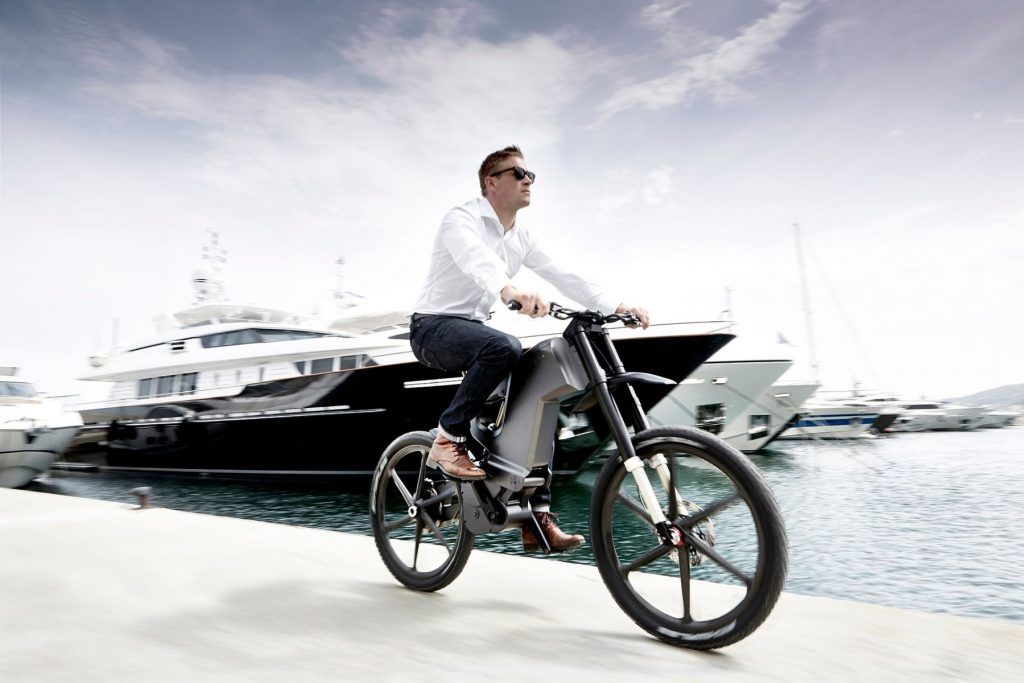 A man is riding a bicycle next to a body of water.