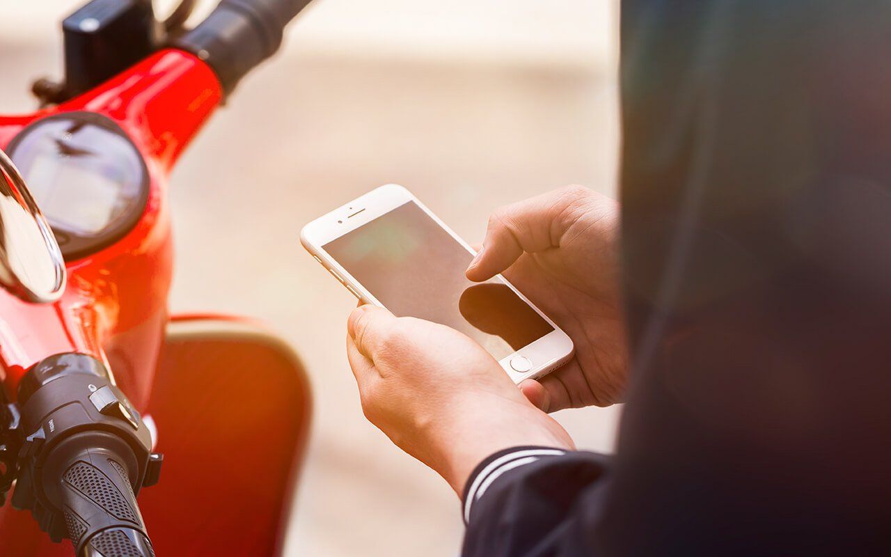 A person is sitting on a scooter using a cell phone.