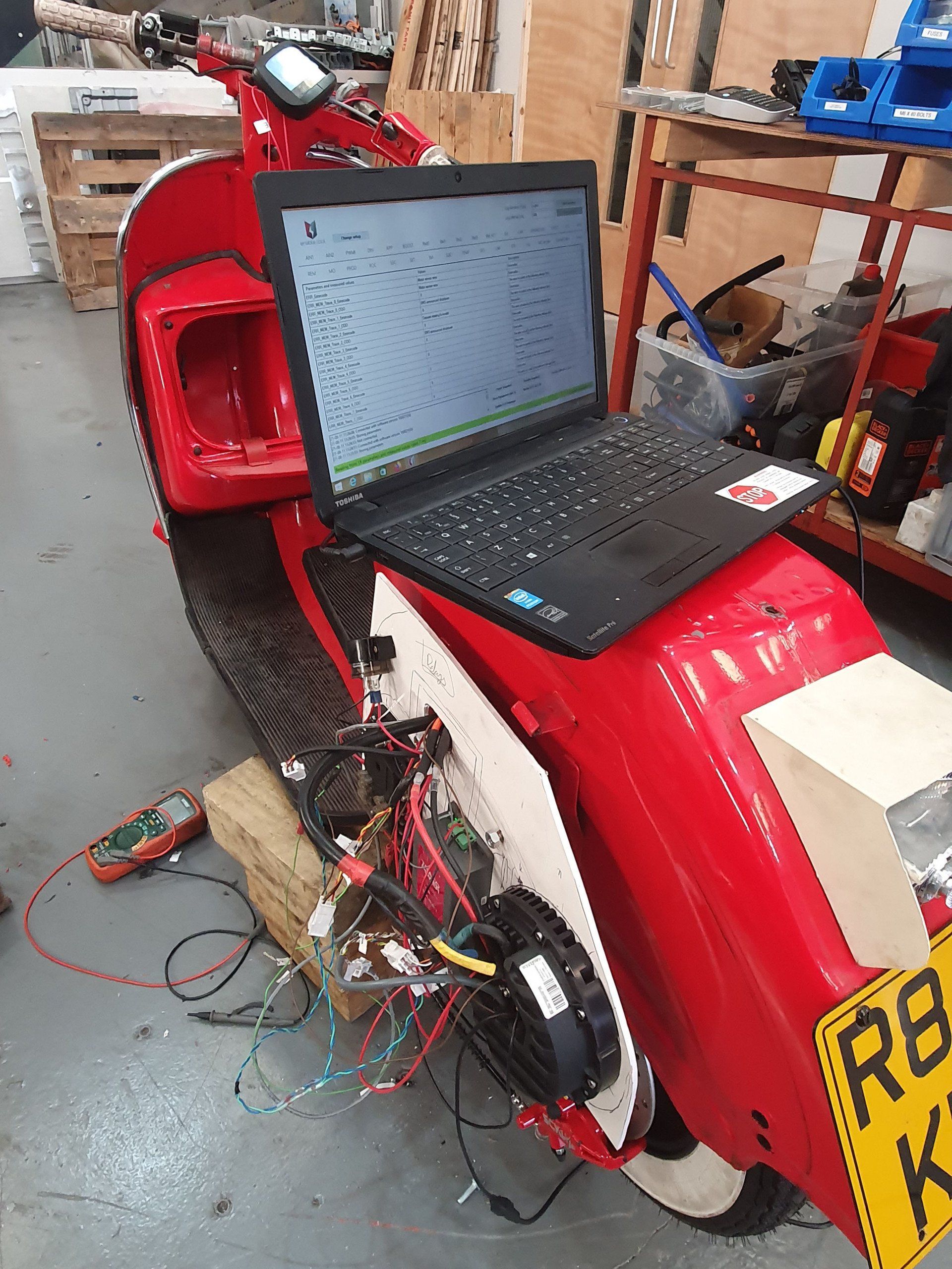 A laptop is sitting on top of a red scooter.