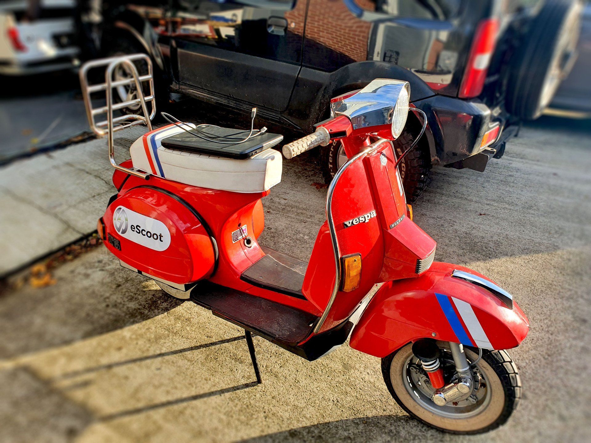 A red vespa scooter is parked on the side of the road