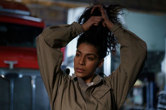 A woman is fixing her hair in a garage.