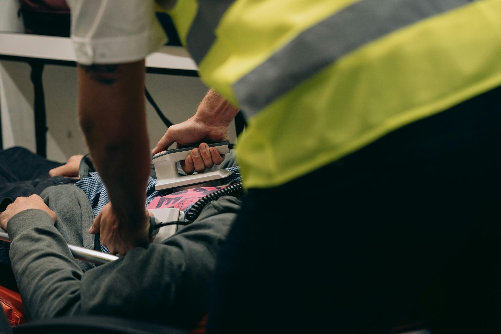 A man is laying on a stretcher in an ambulance while an ambulance driver holds a defibrillator.