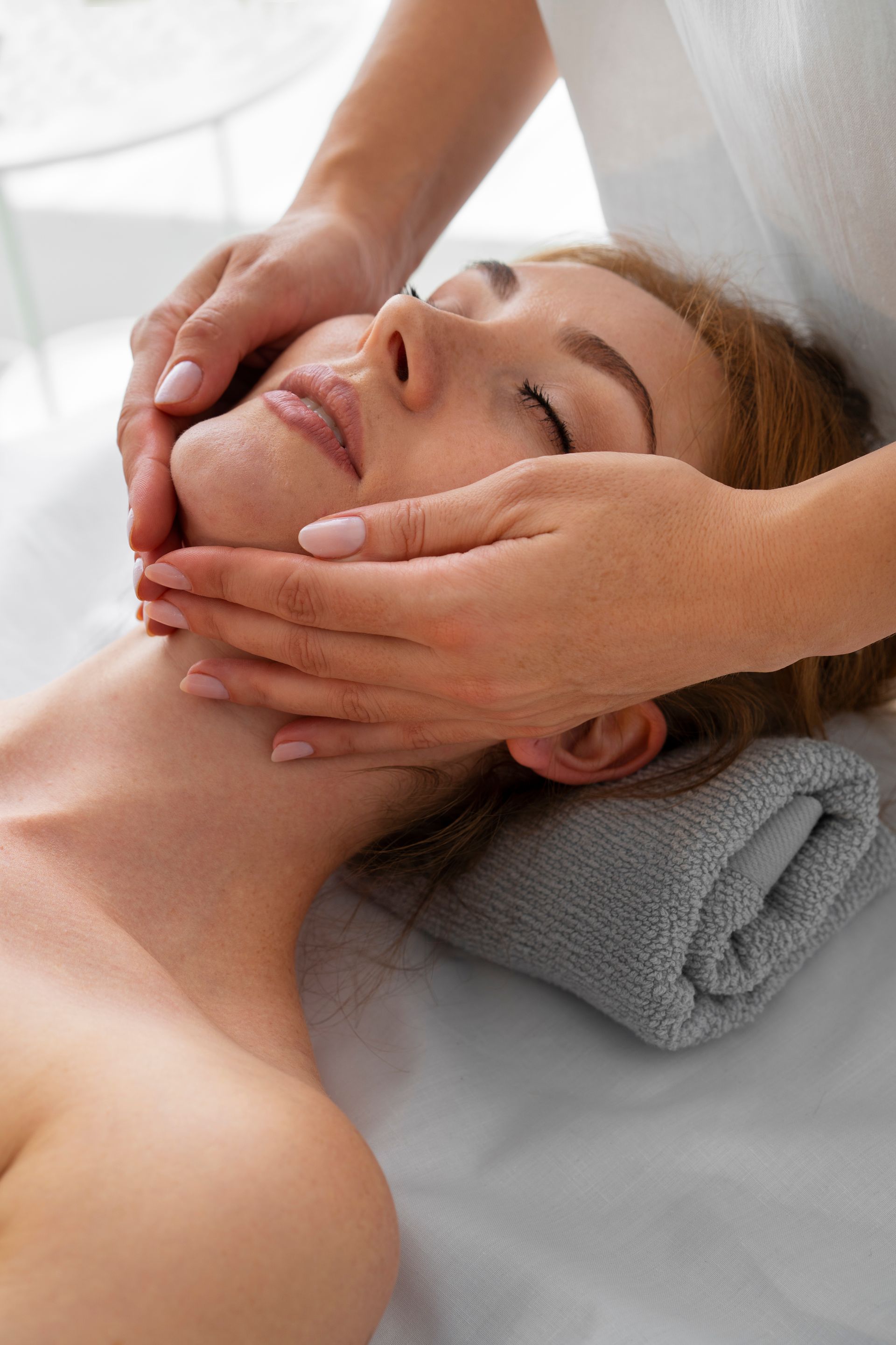 A woman is getting a facial massage at a spa.