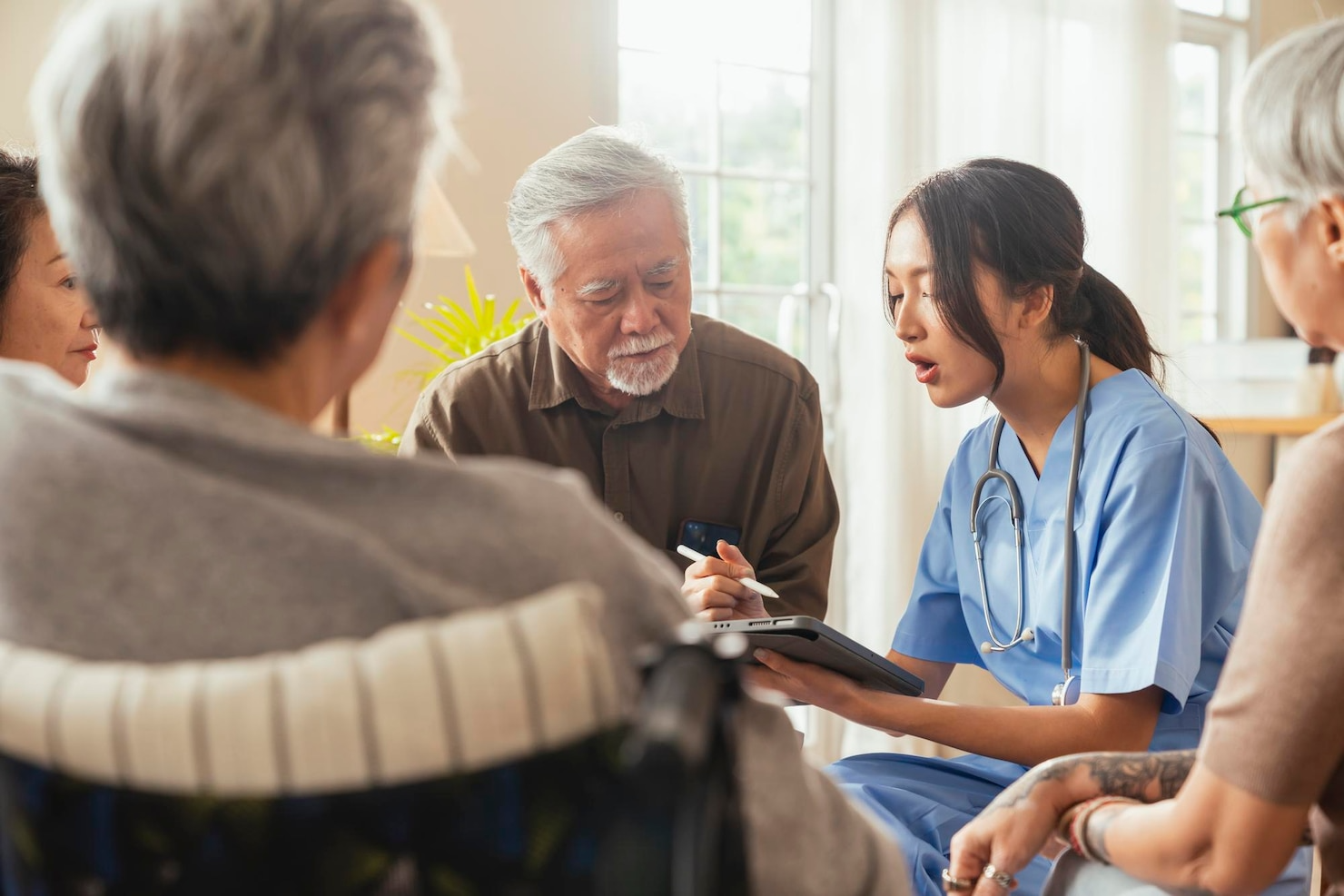A nurse is talking to a group of elderly people in a nursing home.