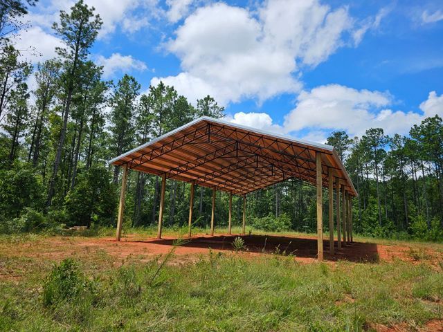 A wooden structure in the middle of a field with trees in the background.