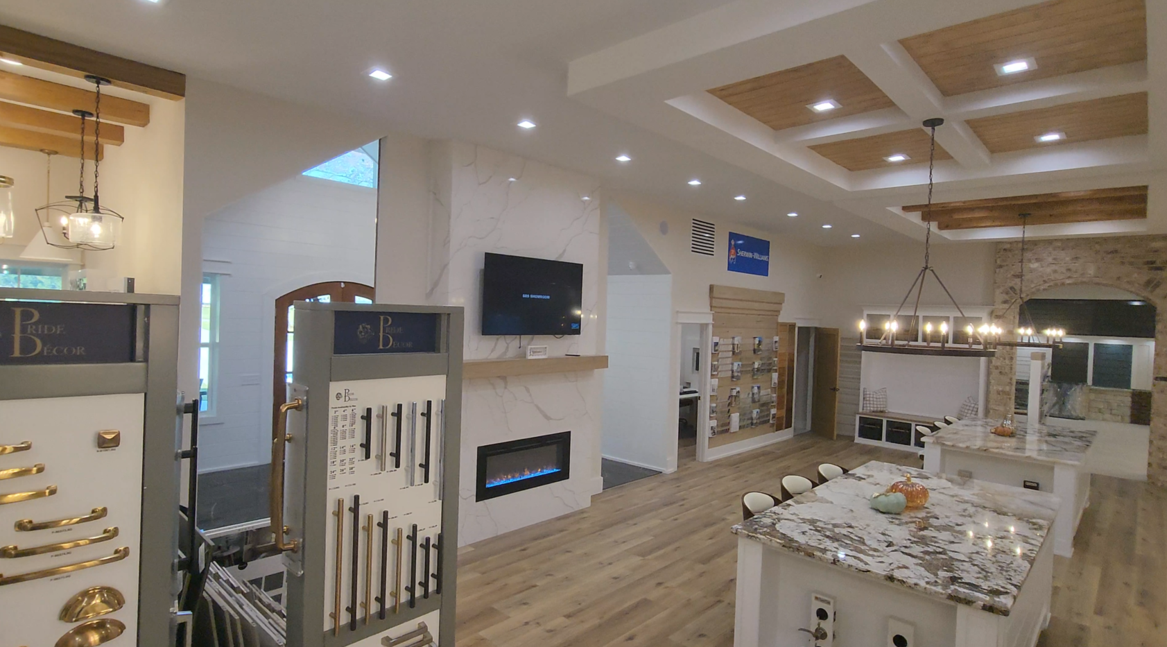 Interior showroom with lighting displays, fireplace, and granite island under a coffered ceiling.