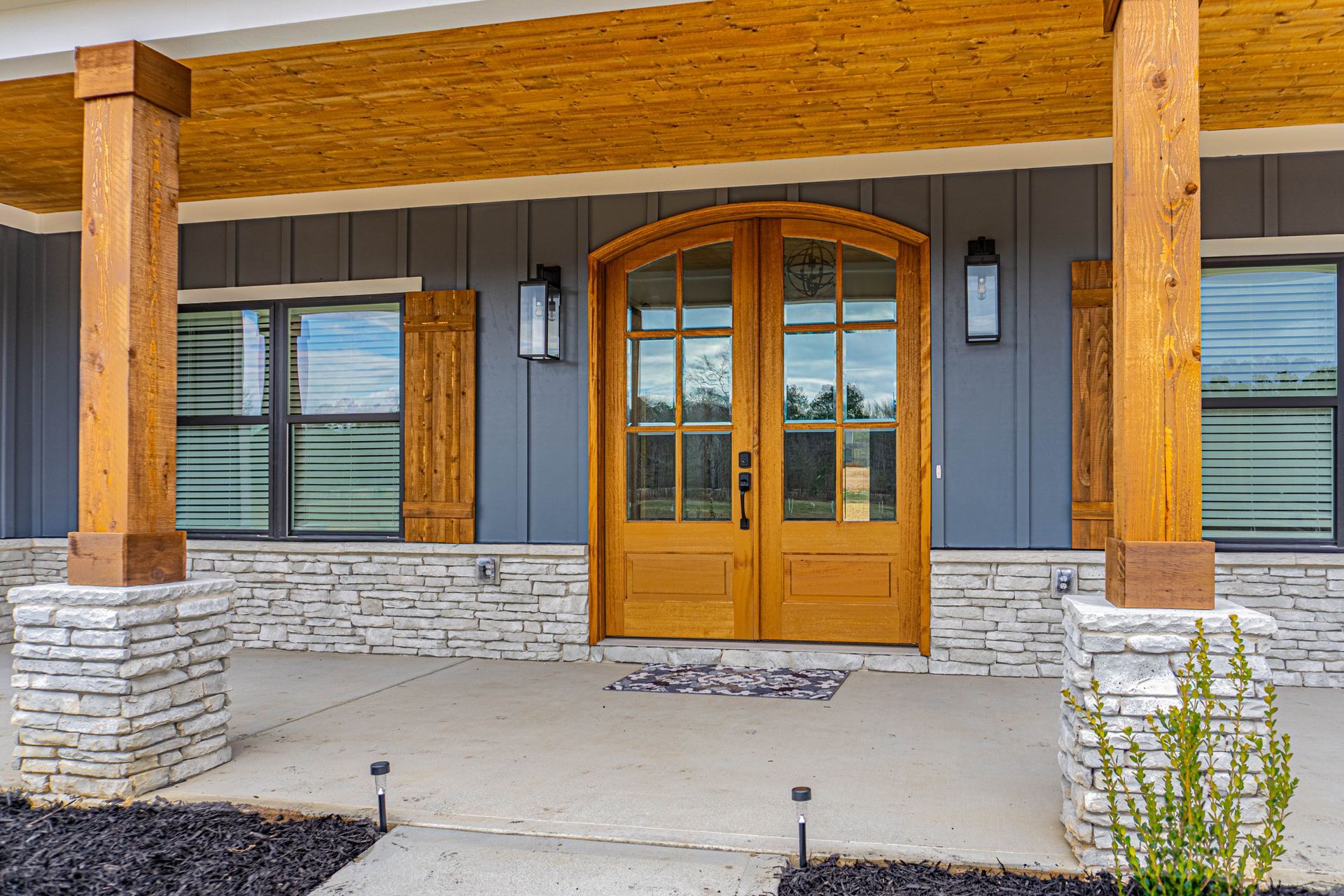 The front of a house with a wooden door and a stone wall.