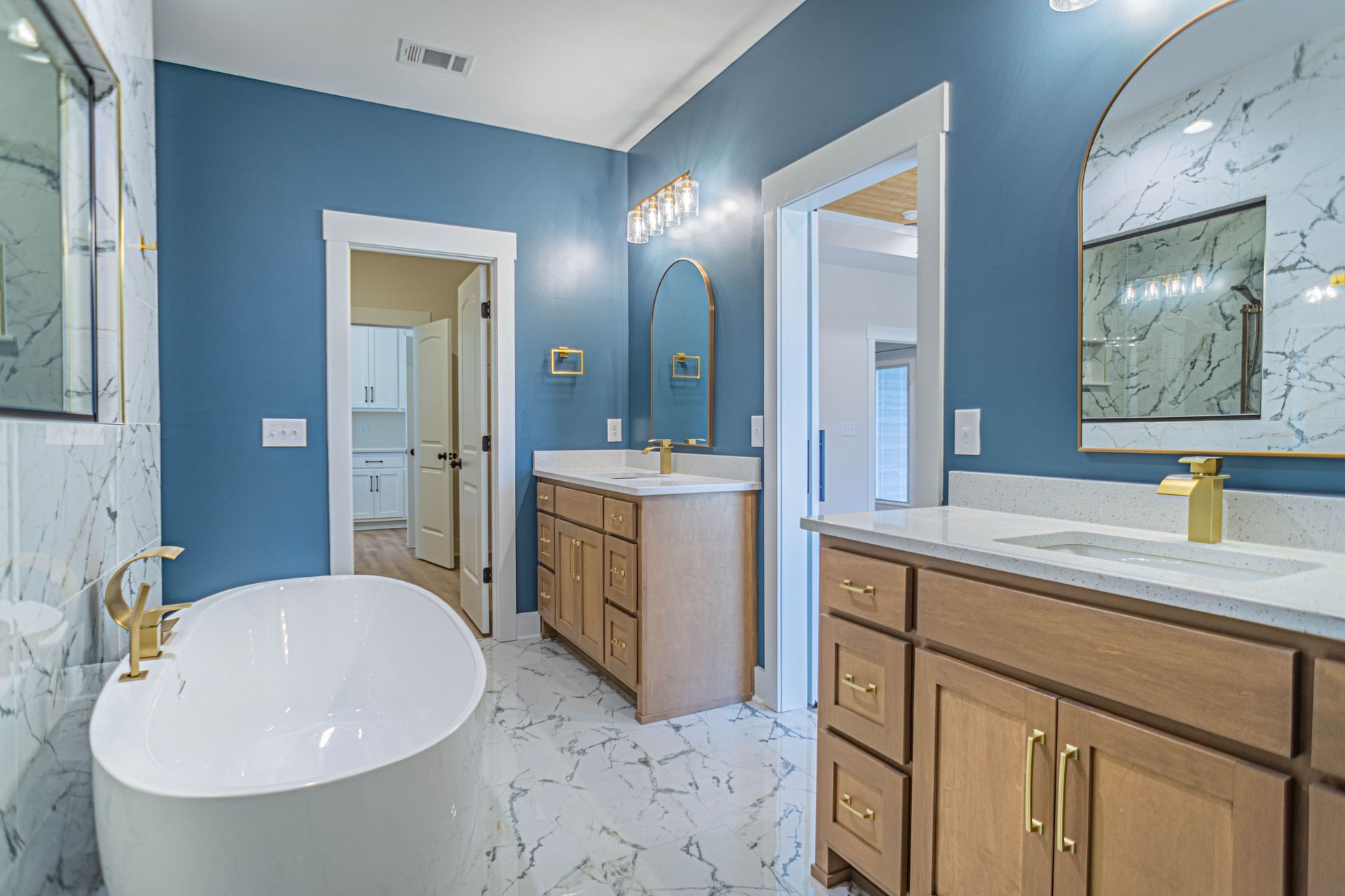 A bathroom with a bathtub , sinks , mirrors and blue walls.