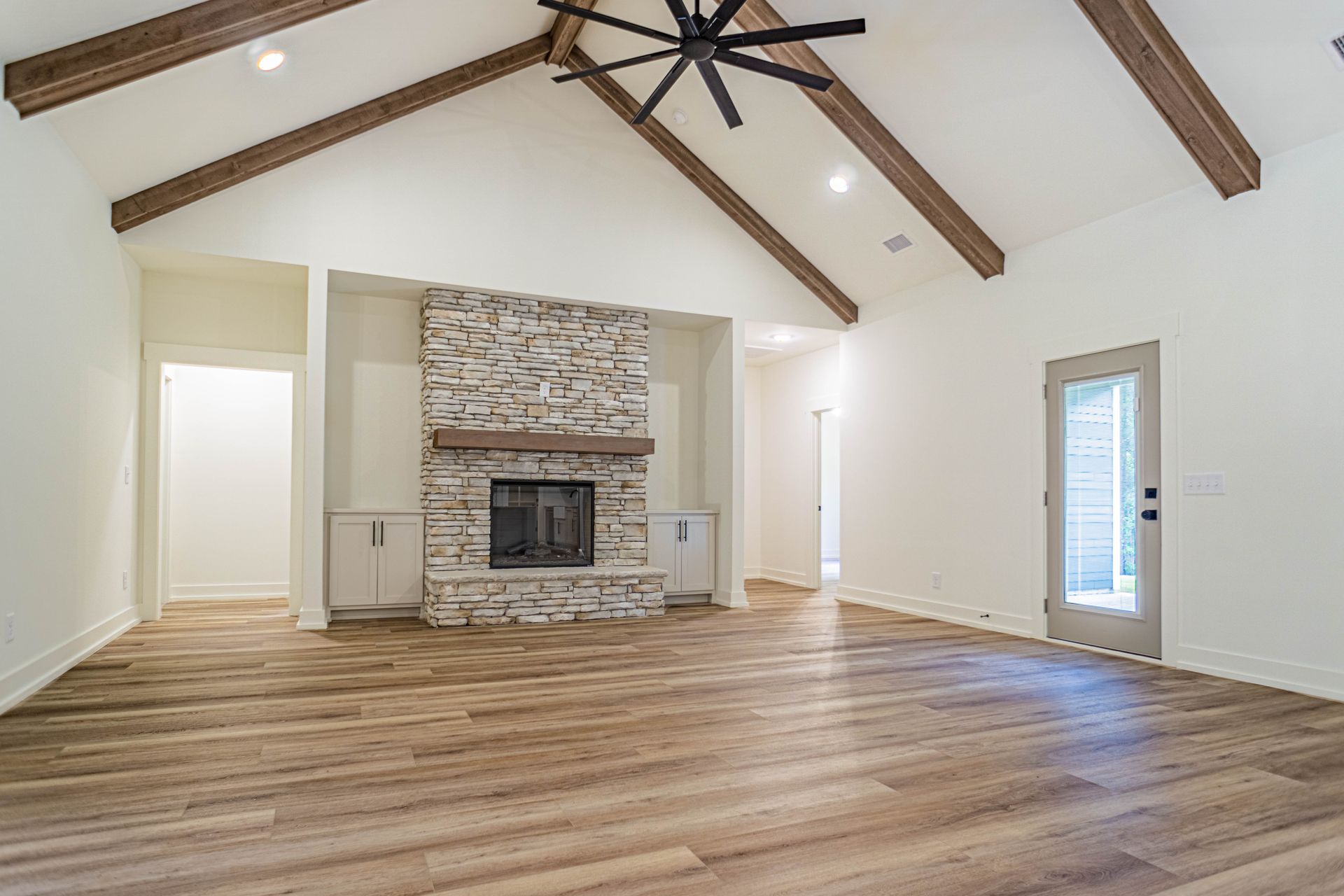 An empty living room with a fireplace and a ceiling fan.