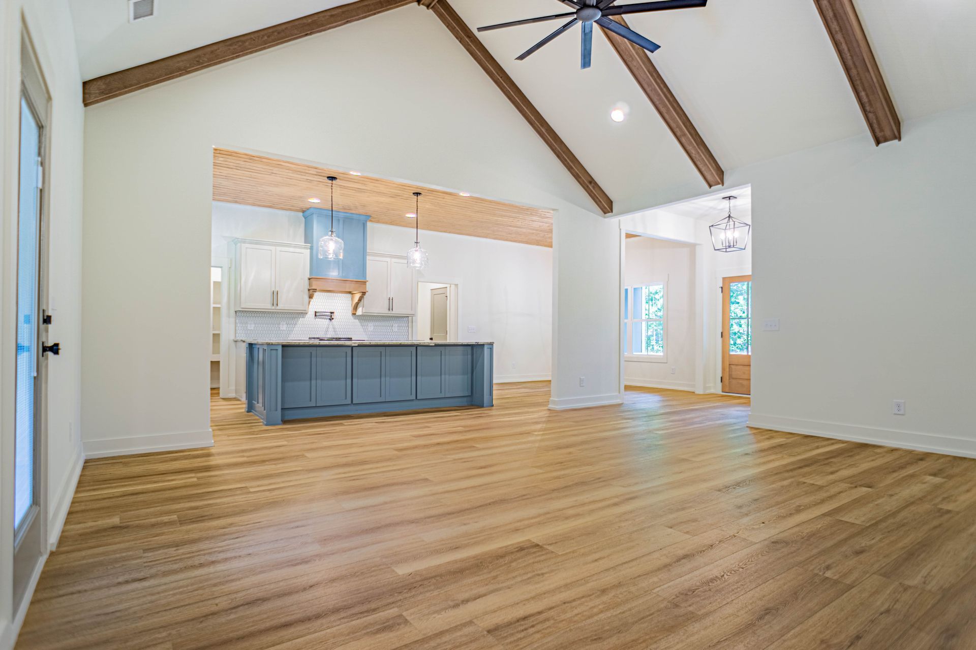 A large empty room with hardwood floors and a ceiling fan.