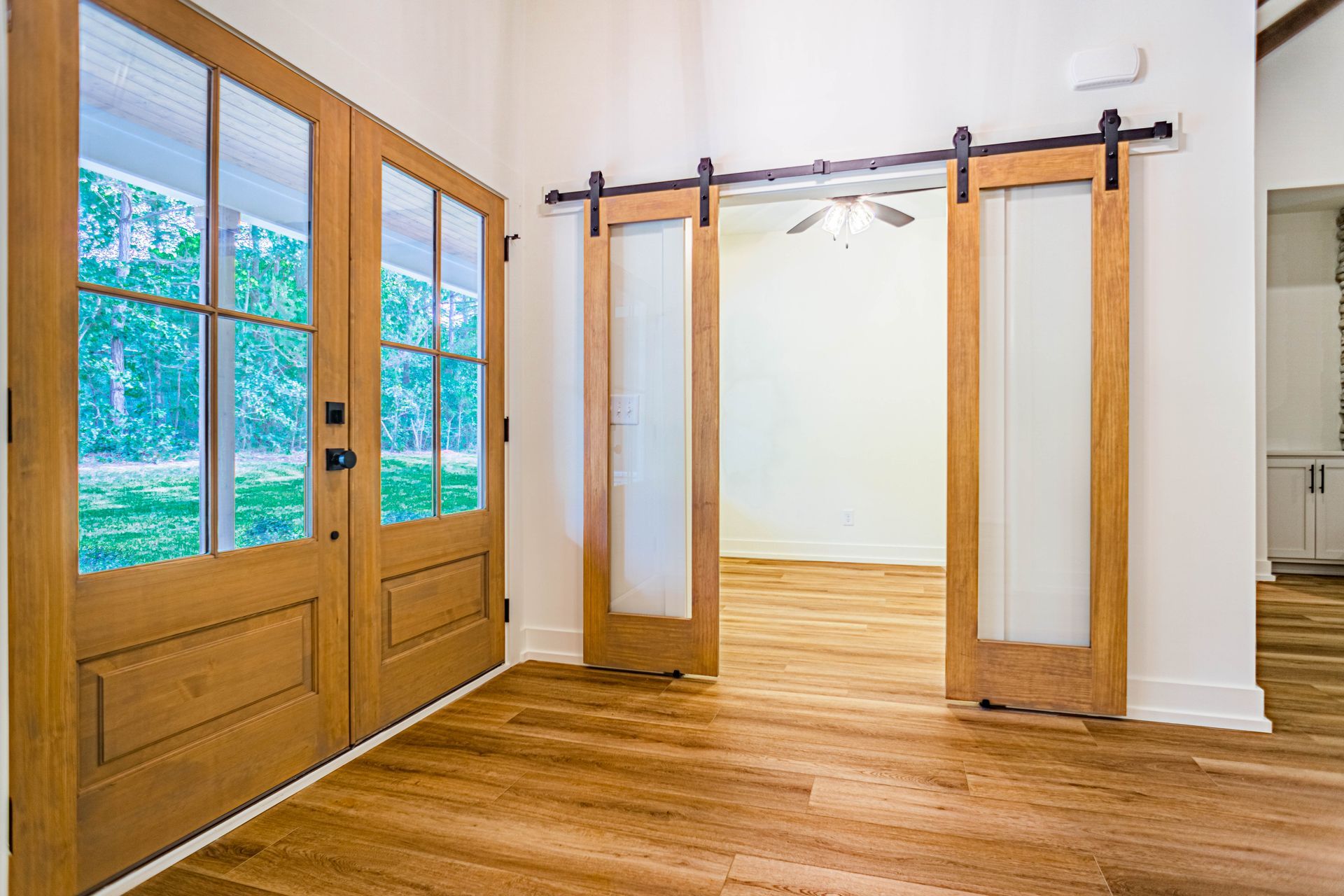 An empty room with sliding barn doors and hardwood floors.