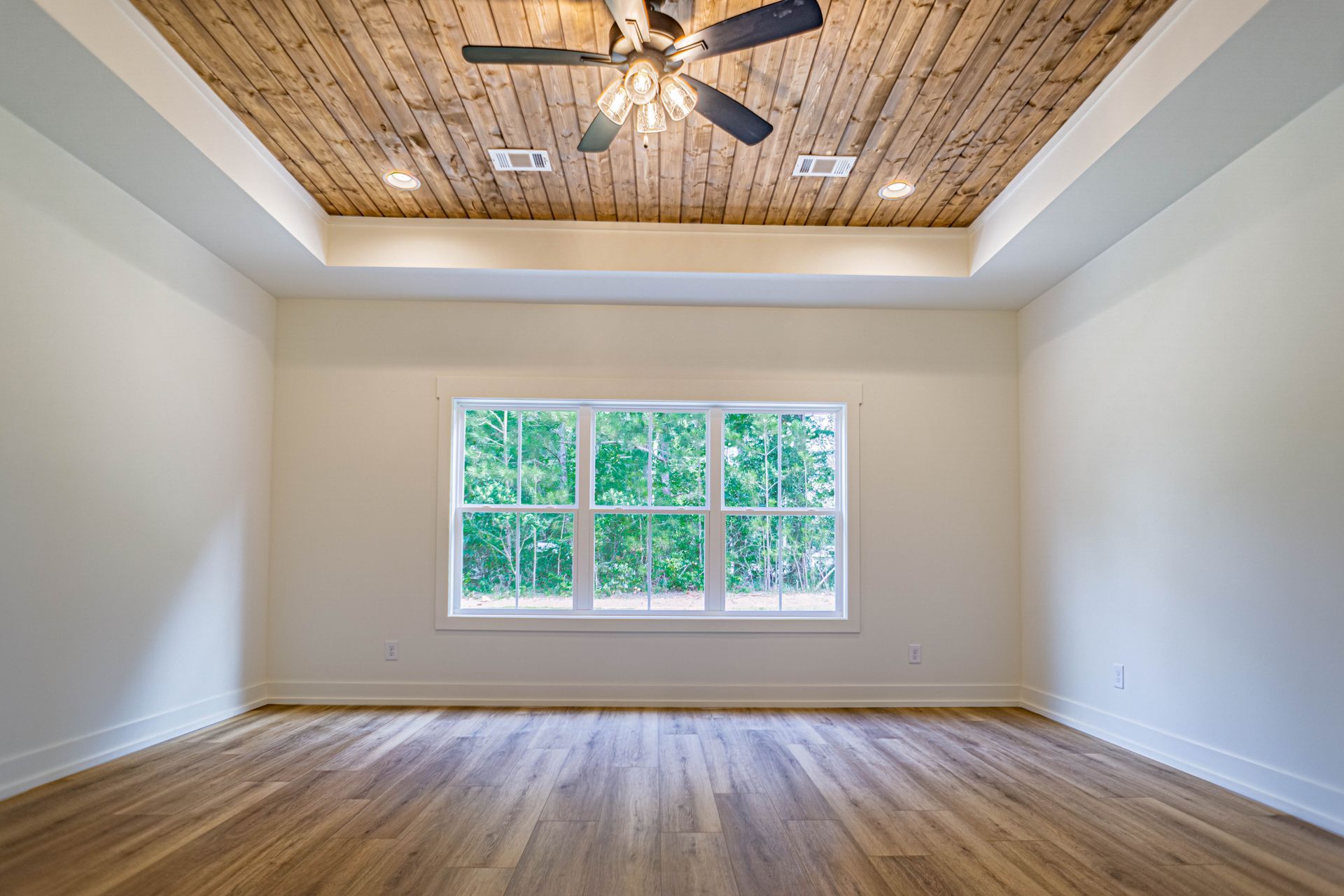 An empty room with a wooden ceiling and a ceiling fan.