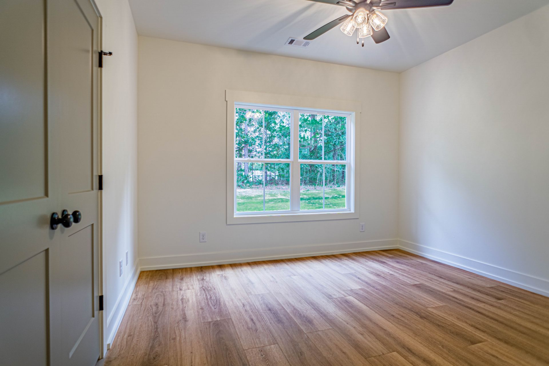 An empty bedroom with hardwood floors and a ceiling fan.