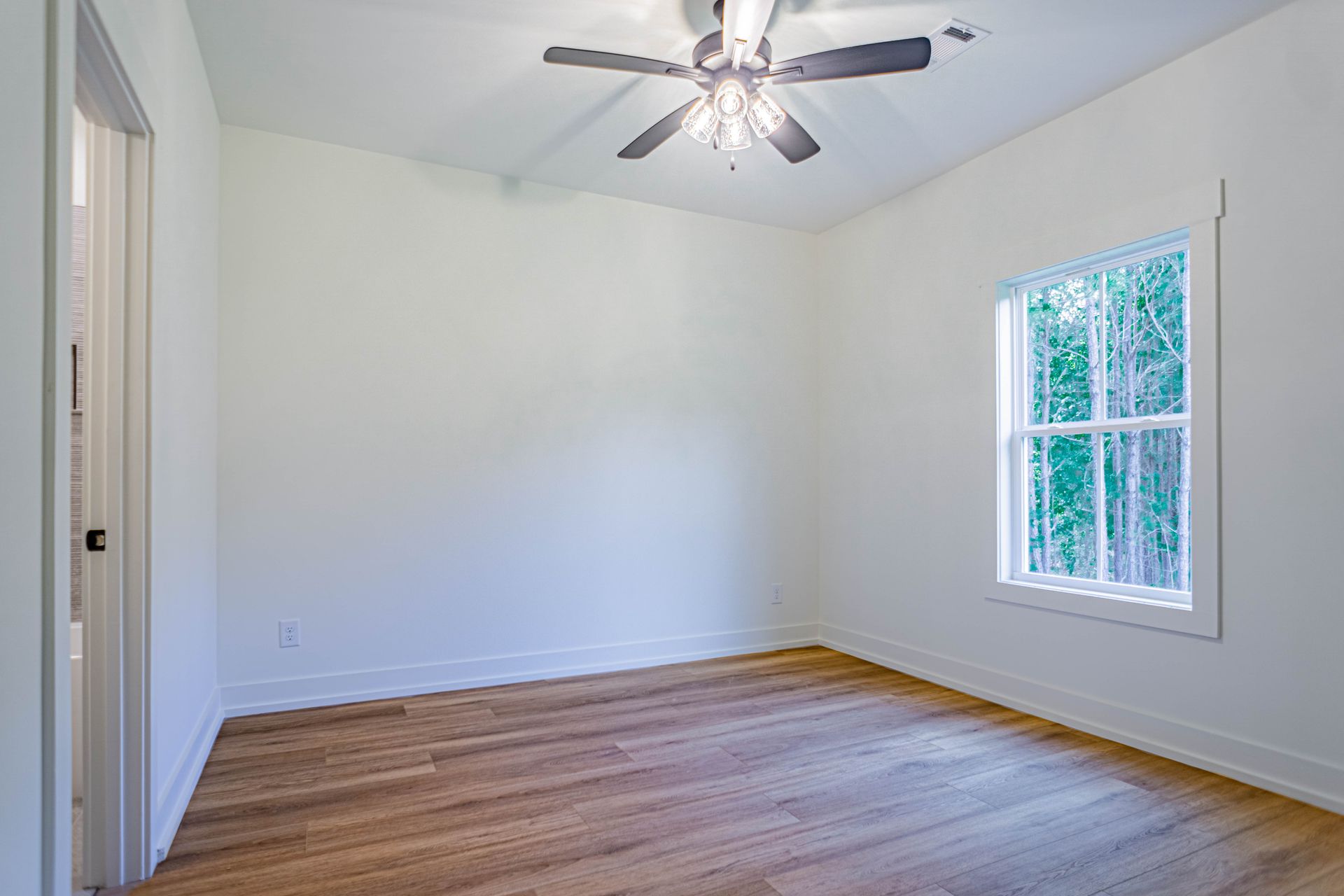 An empty bedroom with hardwood floors and a ceiling fan.
