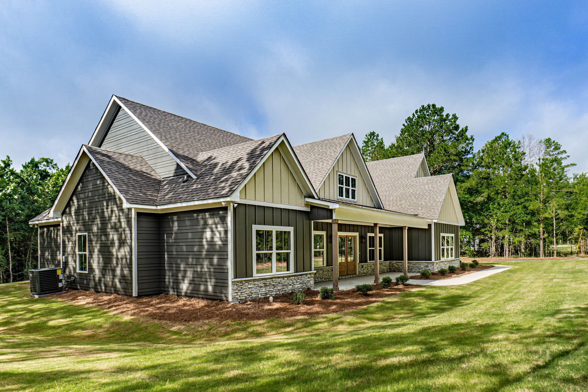 A large house with a large porch is sitting on top of a lush green field.