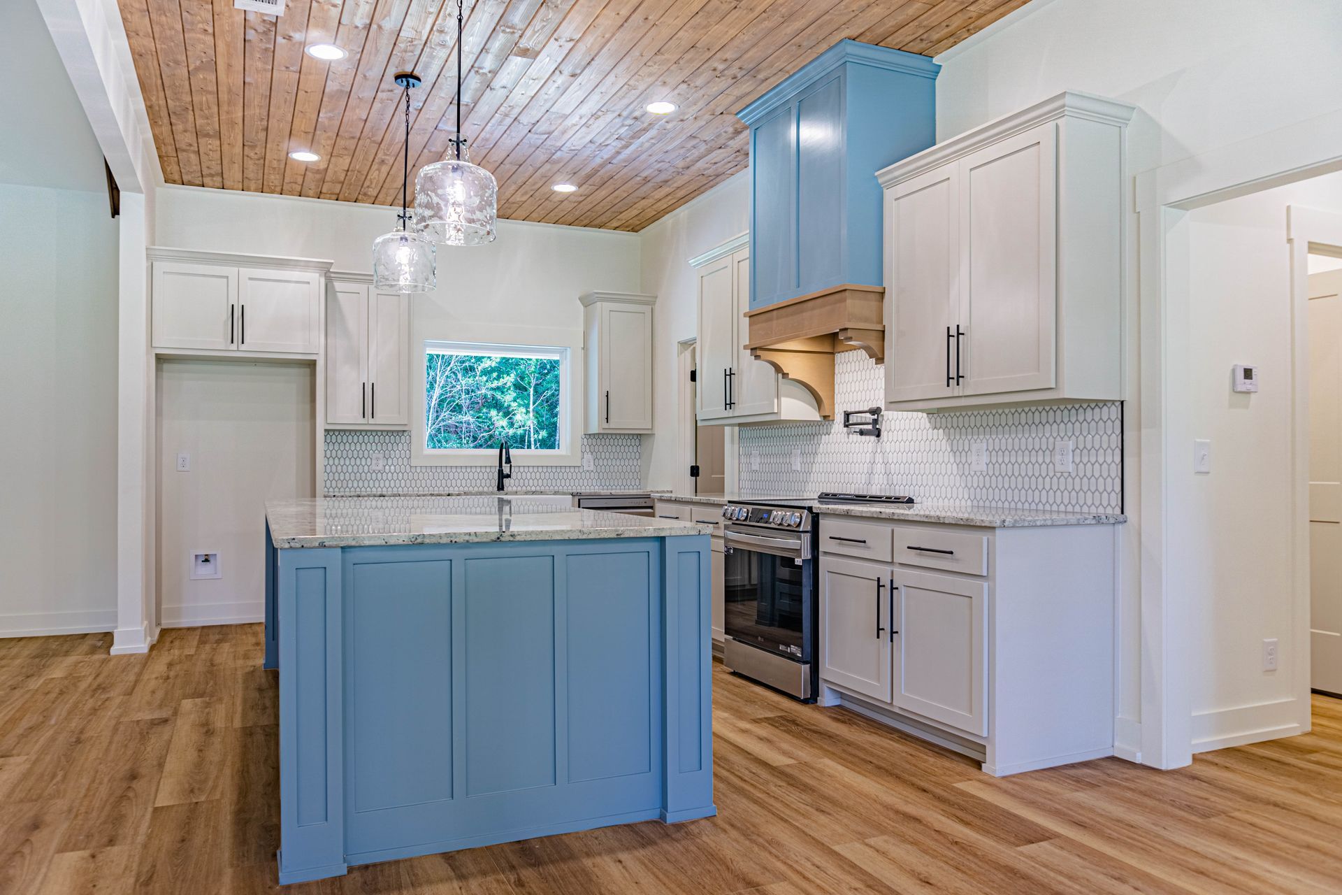 A kitchen with blue cabinets , white cabinets , stainless steel appliances and a large island.