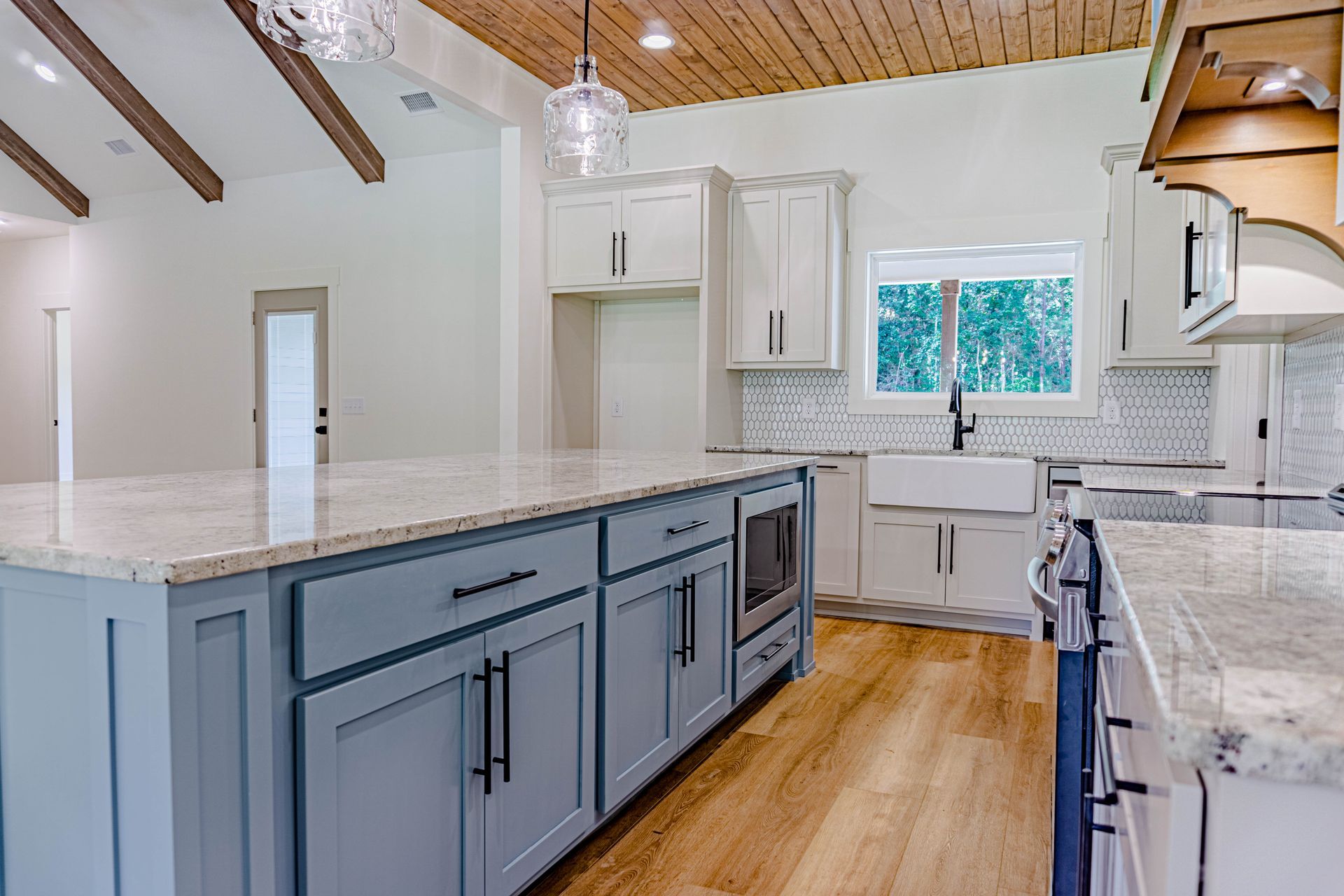 A kitchen with white cabinets , granite counter tops , and a large island.