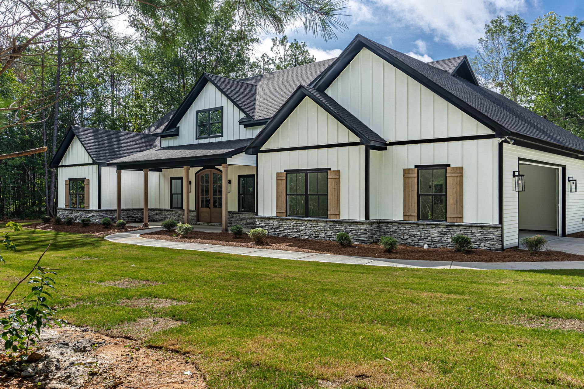A large white house with a black roof is sitting on top of a lush green field.