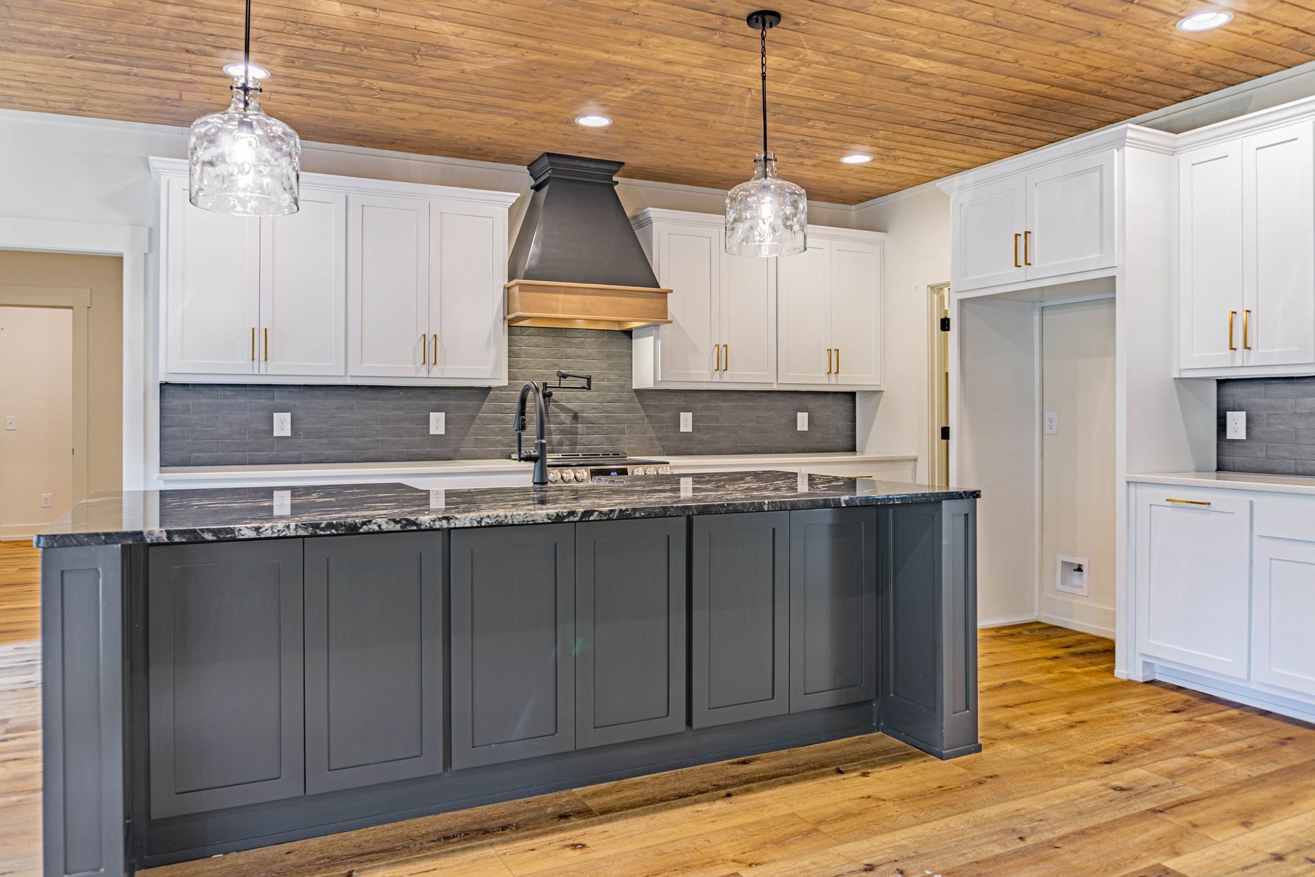 A kitchen with gray cabinets and white cabinets and a wooden ceiling.