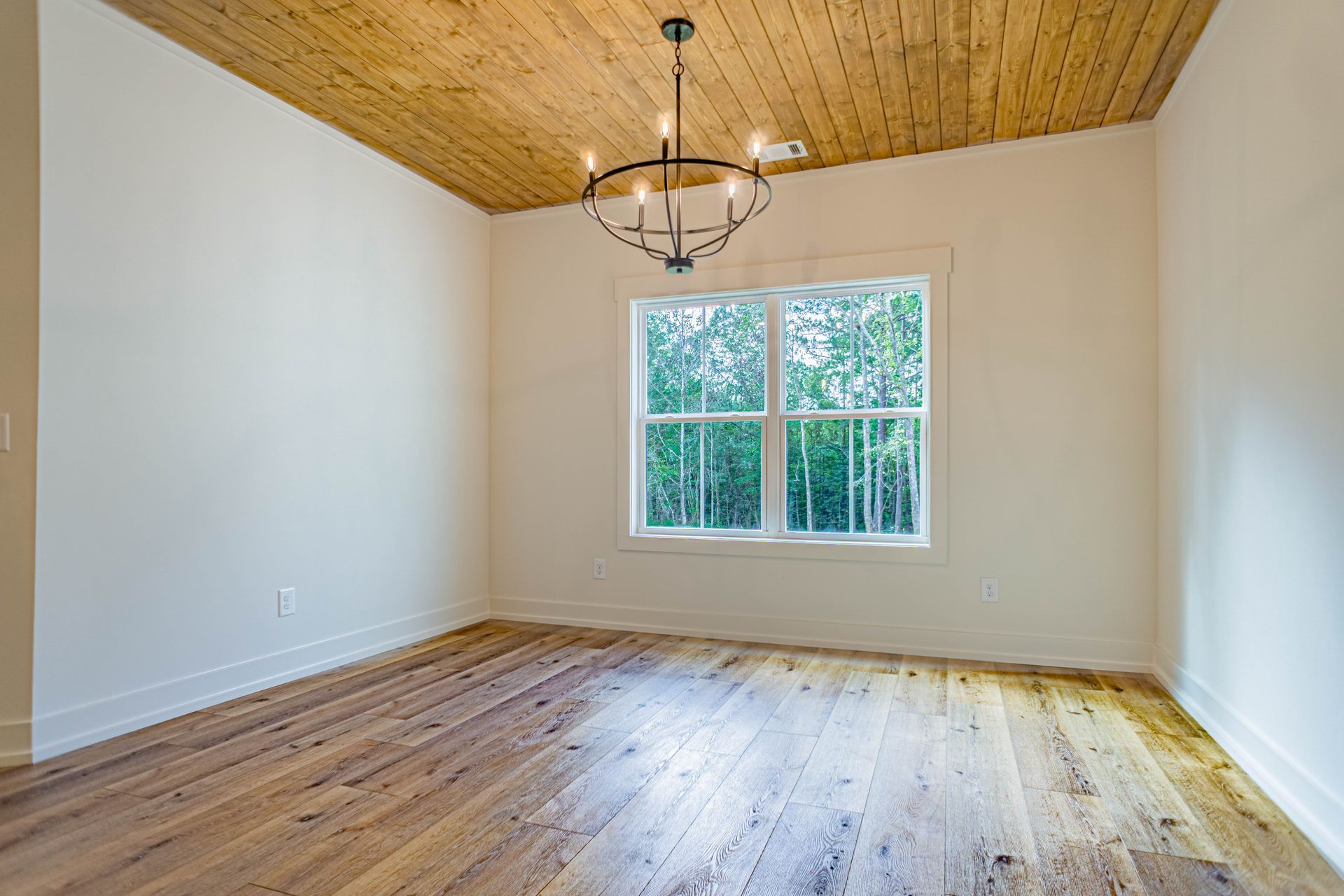 An empty room with wooden floors and a chandelier.