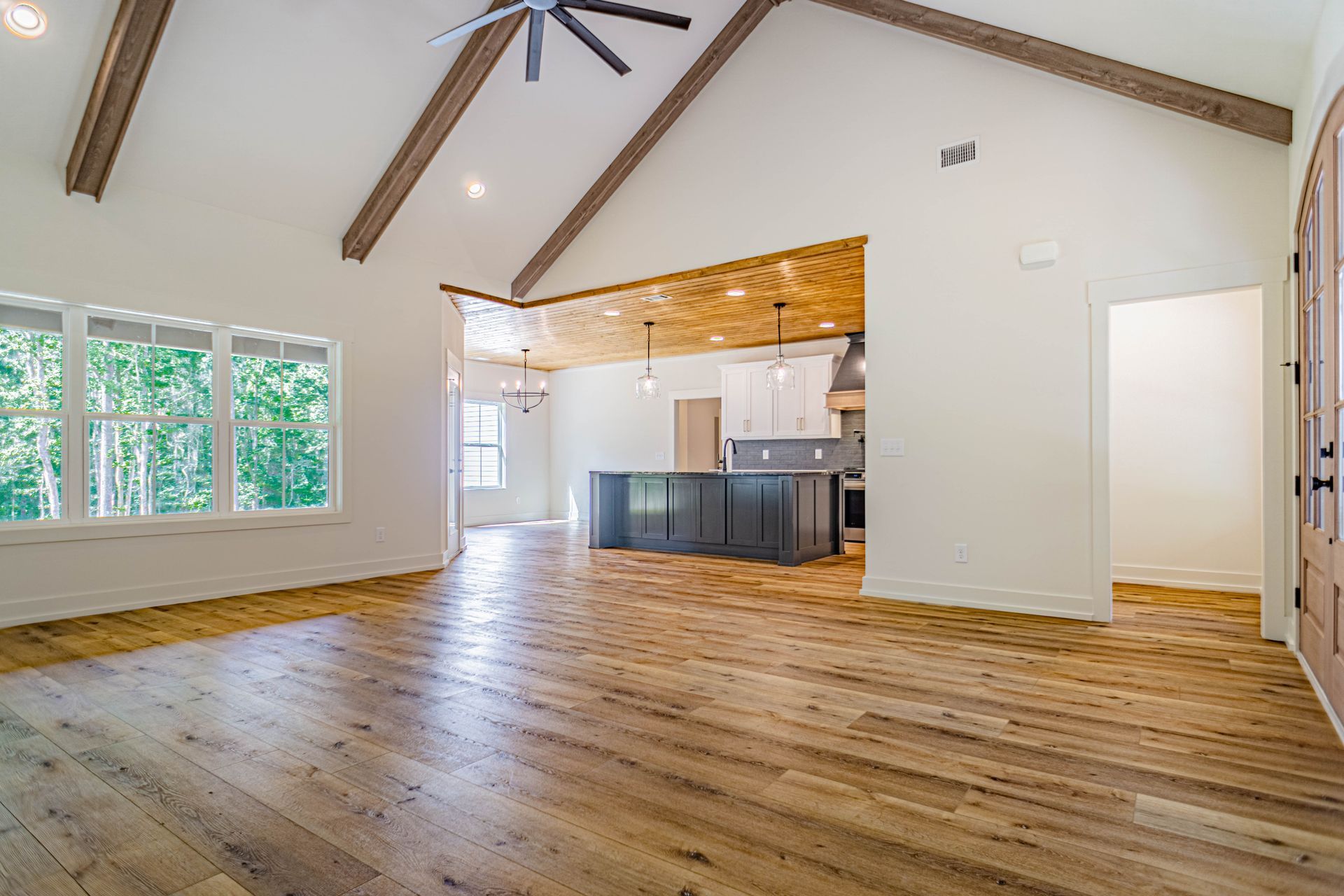A large empty room with hardwood floors and a vaulted ceiling.
